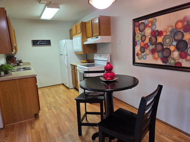 4 Pine Tree Dr Unit 218, Arden Hills, MN 55112 - kitchen featuring under cabinet range hood, white appliances, brown cabinetry, light wood-type flooring, and light countertops