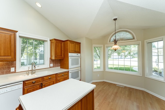 1954 Topaz Pointe Ln SW, Rochester, MN 55902 - kitchen featuring white appliances, vaulted ceiling, brown cabinets, light countertops, and tasteful backsplash