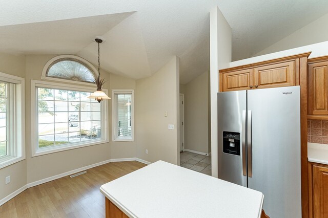 1954 Topaz Pointe Ln SW, Rochester, MN 55902 - kitchen with stainless steel fridge, vaulted ceiling, light countertops, brown cabinets, and light wood-style flooring