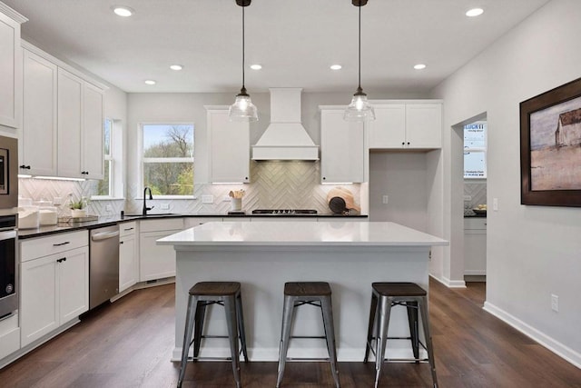 TBB Trinity, Shakopee, MN 55379 - kitchen with appliances with stainless steel finishes, custom range hood, a kitchen breakfast bar, white cabinets, and decorative backsplash