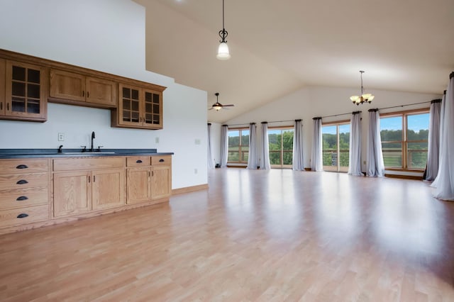 615 18th St, Prairie Lake Twp, WI 54728 - kitchen with dark countertops, glass insert cabinets, high vaulted ceiling, light wood-style floors, and hanging light fixtures