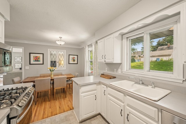 3420 Parkview Blvd, Robbinsdale, MN 55422 - kitchen with light countertops, white cabinetry, stainless steel gas range, a peninsula, and a textured ceiling