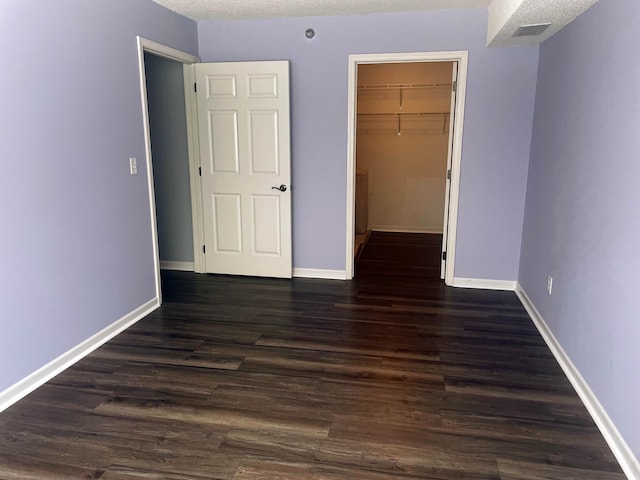 2012 11th Ave SE Unit B, Rochester, MN 55904 - unfurnished bedroom featuring a walk in closet, dark wood finished floors, a closet, and a textured ceiling