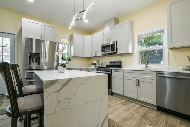 4220 Brookside Ave, Saint Louis Park, MN 55416 - kitchen featuring appliances with stainless steel finishes, light stone counters, a breakfast bar, light wood-type flooring, and healthy amount of natural light