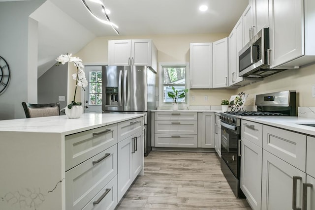 4220 Brookside Ave, Saint Louis Park, MN 55416 - kitchen with appliances with stainless steel finishes, light wood finished floors, light stone counters, vaulted ceiling, and a kitchen island
