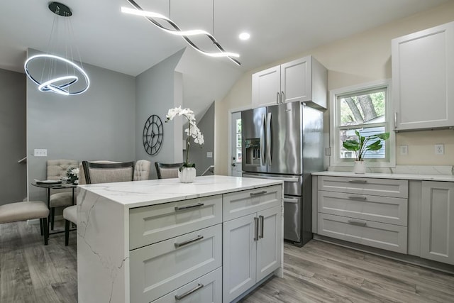 4220 Brookside Ave, Saint Louis Park, MN 55416 - kitchen with stainless steel fridge, a chandelier, wood finished floors, light stone countertops, and a center island