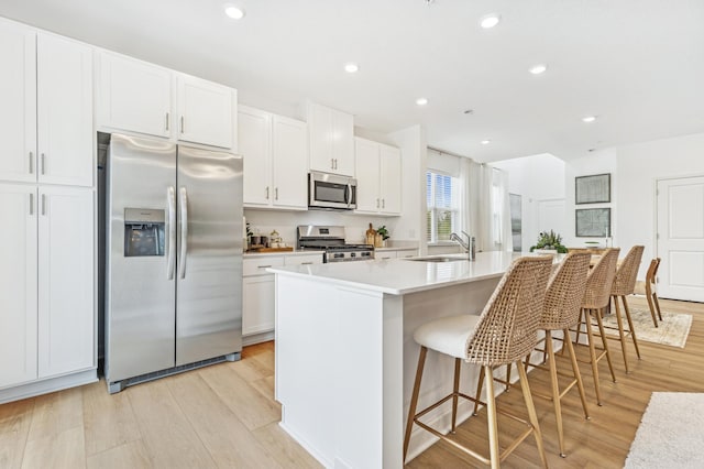 5413 Queens Dr NW, Rochester, MN 55901 - kitchen featuring appliances with stainless steel finishes, a kitchen island with sink, light wood-type flooring, white cabinets, and recessed lighting