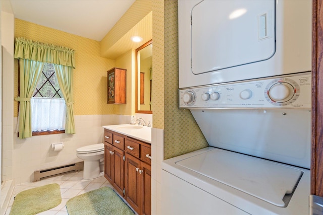25761 Echo Bay Rd, Bay Lake Twp, MN 56444 - laundry room featuring stacked washer / drying machine, a baseboard radiator, wallpapered walls, light tile patterned floors, and a wainscoted wall