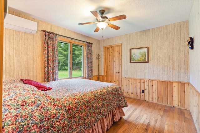 25761 Echo Bay Rd, Bay Lake Twp, MN 56444 - bedroom with hardwood / wood-style flooring, a wall mounted air conditioner, wood walls, wallpapered walls, and a wainscoted wall