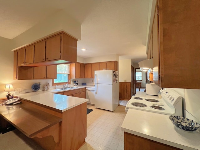 1804 7th St SW, Willmar, MN 56201 - kitchen with white appliances, a peninsula, ventilation hood, light countertops, and brown cabinetry