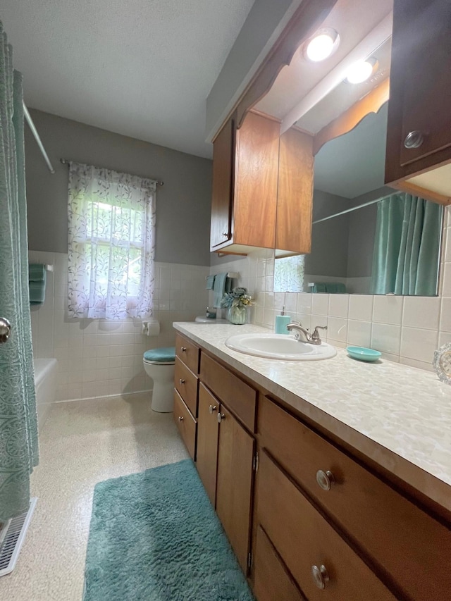 1804 7th St SW, Willmar, MN 56201 - full bathroom featuring vanity, shower / bath combo with shower curtain, tile walls, and a wainscoted wall