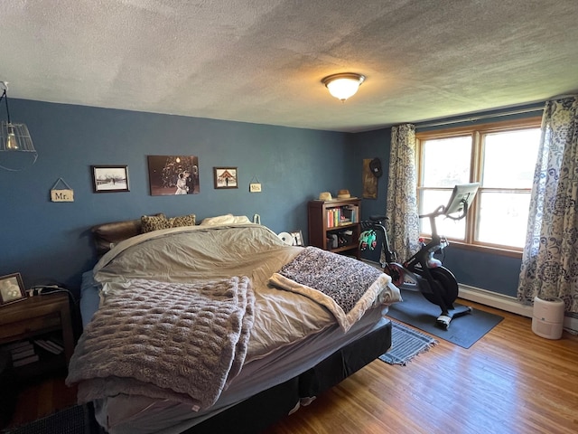 912 3rd St NE, Roseau, MN 56751 - bedroom featuring a textured ceiling, wood finished floors, and a baseboard heating unit