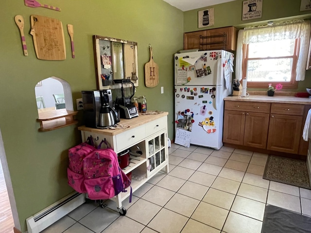912 3rd St NE, Roseau, MN 56751 - kitchen with freestanding refrigerator, brown cabinetry, light tile patterned floors, light countertops, and a baseboard radiator
