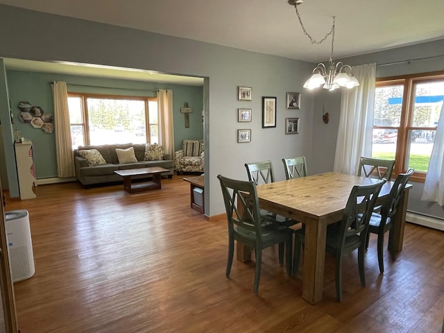 912 3rd St NE, Roseau, MN 56751 - dining area with a chandelier, wood finished floors, and a baseboard heating unit
