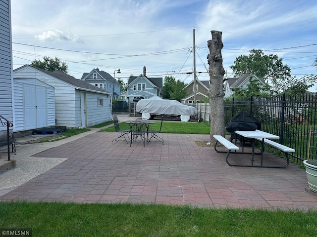 653 Thomas Ave, Saint Paul, MN 55104 - fenced backyard with outdoor dining area, a patio, a storage unit, and a residential view