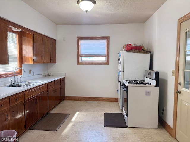 653 Thomas Ave, Saint Paul, MN 55104 - kitchen featuring white range with gas cooktop, light countertops, healthy amount of natural light, light flooring, and a textured ceiling