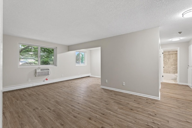 4371 Wilshire Blvd Unit 107, Mound, MN 55364 - empty room featuring baseboard heating, wood finished floors, a wall mounted AC, and a textured ceiling