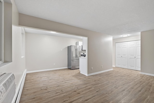 4371 Wilshire Blvd Unit 107, Mound, MN 55364 - unfurnished living room featuring light wood-type flooring, a textured ceiling, and a wall mounted AC