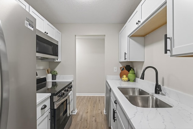 4371 Wilshire Blvd Unit 107, Mound, MN 55364 - kitchen with stainless steel appliances, light wood-type flooring, light stone counters, white cabinetry, and a textured ceiling