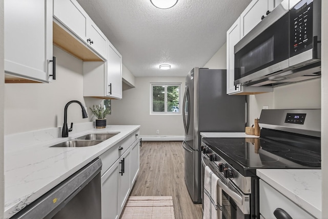 4371 Wilshire Blvd Unit 107, Mound, MN 55364 - kitchen featuring stainless steel appliances, a textured ceiling, white cabinetry, light wood-type flooring, and light stone counters