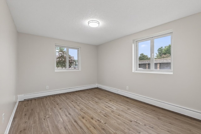 4371 Wilshire Blvd Unit 107, Mound, MN 55364 - spare room with baseboard heating, wood finished floors, and a textured ceiling