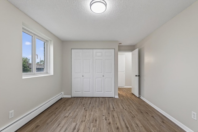 4371 Wilshire Blvd Unit 107, Mound, MN 55364 - unfurnished bedroom with a baseboard heating unit, wood finished floors, a closet, and a textured ceiling