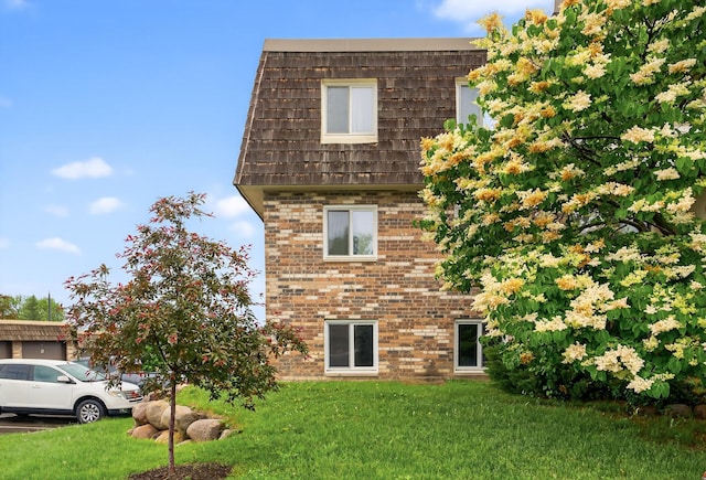 4371 Wilshire Blvd Unit 107, Mound, MN 55364 - view of property exterior featuring brick siding, mansard roof, and a yard