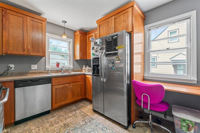 1622 3rd St NE, Rochester, MN 55906 - kitchen featuring stainless steel appliances, brown cabinets, light stone finish flooring, decorative light fixtures, and light countertops