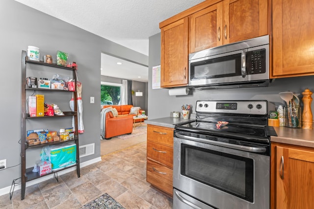 1622 3rd St NE, Rochester, MN 55906 - kitchen featuring appliances with stainless steel finishes, brown cabinets, and stone finish floors