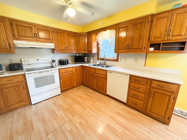 1908 Summit Ave, Worthington, MN 56187 - kitchen with white appliances, under cabinet range hood, brown cabinets, and light wood-type flooring