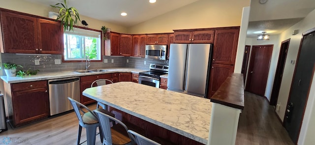961 39 1/2 Ave W, West Fargo, ND 58078 - kitchen featuring appliances with stainless steel finishes, light wood-style flooring, decorative backsplash, lofted ceiling, and light countertops