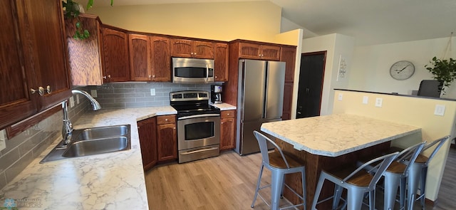 961 39 1/2 Ave W, West Fargo, ND 58078 - kitchen featuring stainless steel appliances, a kitchen bar, backsplash, light countertops, and lofted ceiling