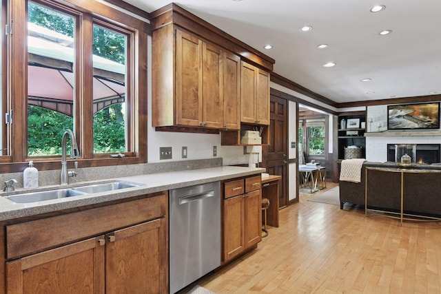 10301 Brunswick Cir, Bloomington, MN 55438 - kitchen with dishwasher, recessed lighting, brown cabinets, light wood-type flooring, and a warm lit fireplace