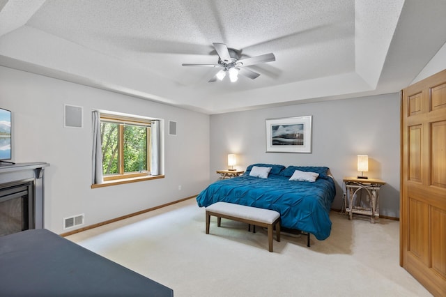 13756 Skyline Cir, Louisville Twp, MN 55379 - bedroom featuring a tray ceiling, light carpet, a textured ceiling, ceiling fan, and a glass covered fireplace