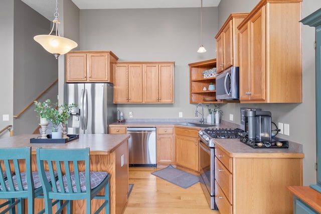 9769 Pinehurst Ct, Elko New Market, MN 55020 - kitchen featuring stainless steel appliances, light wood-style flooring, open shelves, hanging light fixtures, and a kitchen bar
