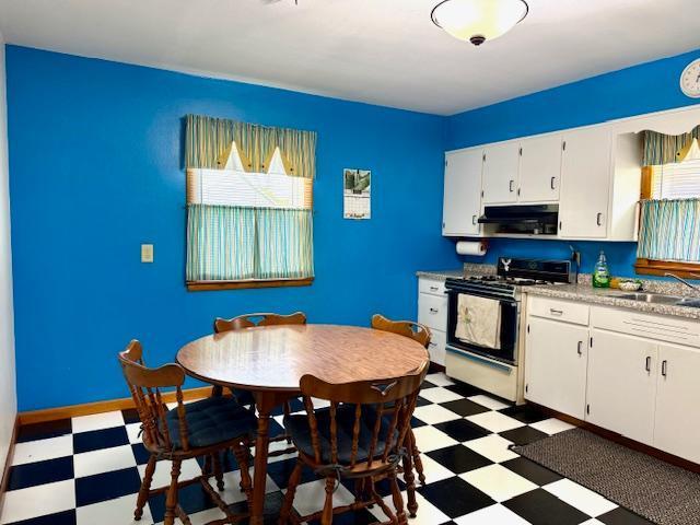 819 Washington St E, Caledonia, MN 55921 - kitchen with gas stove, tile patterned floors, under cabinet range hood, and white cabinetry