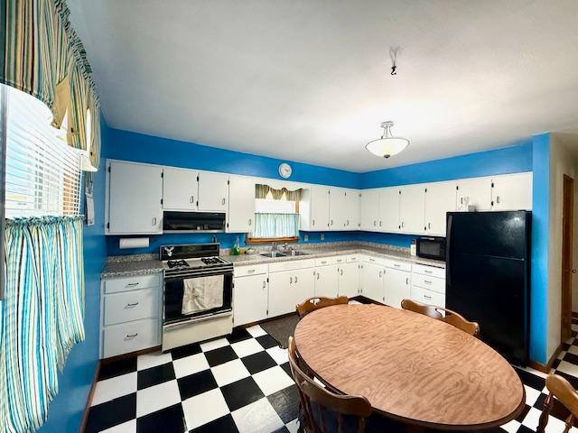 819 Washington St E, Caledonia, MN 55921 - kitchen with black appliances, under cabinet range hood, dark floors, and white cabinetry
