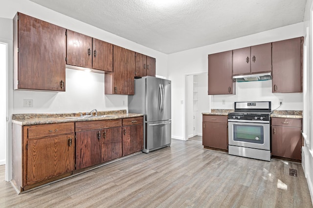2414 3rd St NE, Minneapolis, MN 55418 - kitchen with stainless steel appliances, under cabinet range hood, light wood-style flooring, light countertops, and a textured ceiling