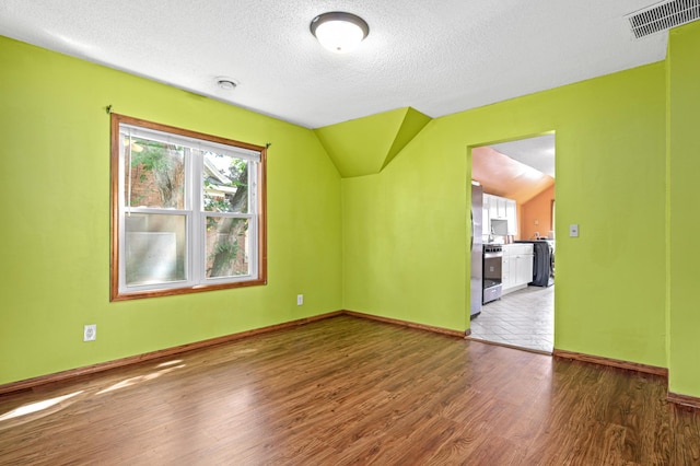 2414 3rd St NE, Minneapolis, MN 55418 - spare room featuring washer / dryer, wood finished floors, a textured ceiling, vaulted ceiling, and a smoke detector