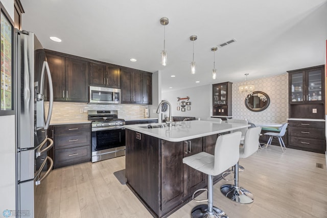 122 15th Ave E, Fargo, ND 58078 - kitchen featuring appliances with stainless steel finishes, light wood-style floors, light countertops, a breakfast bar area, and dark brown cabinets