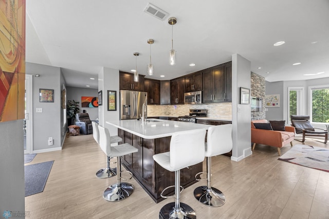 122 15th Ave E, Fargo, ND 58078 - kitchen featuring appliances with stainless steel finishes, open floor plan, light wood-style floors, dark brown cabinets, and light countertops