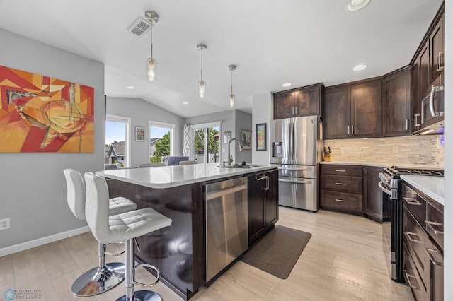 122 15th Ave E, Fargo, ND 58078 - kitchen with appliances with stainless steel finishes, light countertops, recessed lighting, dark brown cabinetry, and a breakfast bar area