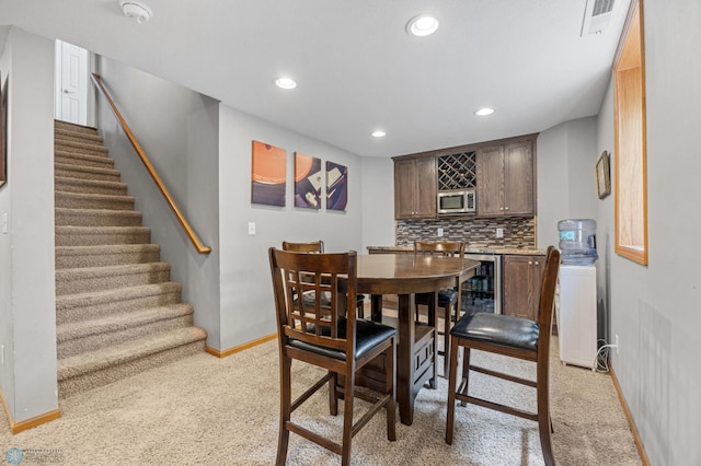 122 15th Ave E, Fargo, ND 58078 - dining room with light carpet, bar area, recessed lighting, stairway, and beverage cooler