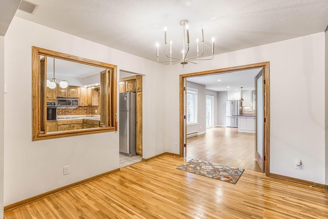 6108 Birchwood Rd, Woodbury, MN 55125 - empty room featuring a chandelier, light wood-style floors, and baseboard heating
