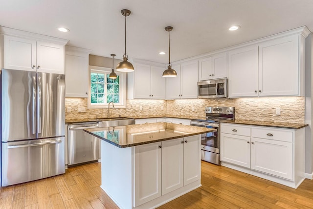 6108 Birchwood Rd, Woodbury, MN 55125 - kitchen featuring stainless steel appliances, white cabinets, a center island, light wood-type flooring, and decorative backsplash