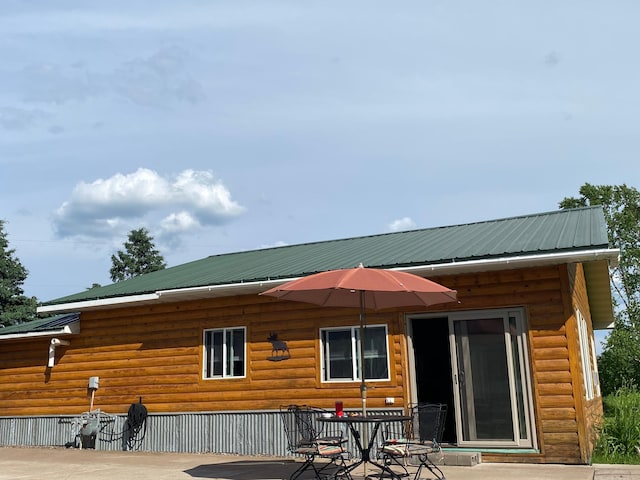 3653 Front St, Barnum, MN 55707 - rear view of house featuring a metal roof, log veneer siding, a patio area, and outdoor dining space