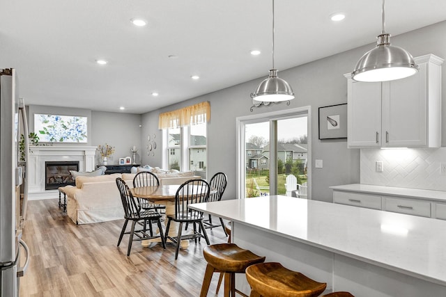 6439 Alvina Ct, Inver Grove Heights, MN 55077 - kitchen with light countertops, recessed lighting, light wood-type flooring, a kitchen bar, and tasteful backsplash