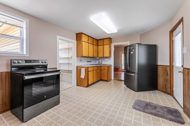 821 5th St, Winona, MN 55987 - kitchen with appliances with stainless steel finishes, light countertops, wainscoting, brown cabinets, and wood walls