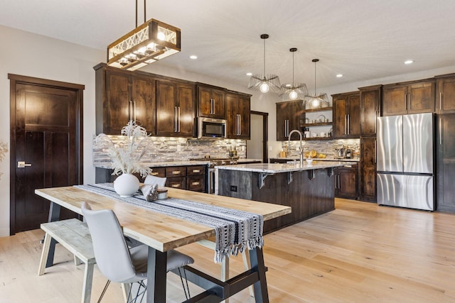12105 285th St, Lindstrom, MN 55045 - kitchen with appliances with stainless steel finishes, dark brown cabinetry, light wood-style flooring, backsplash, and recessed lighting