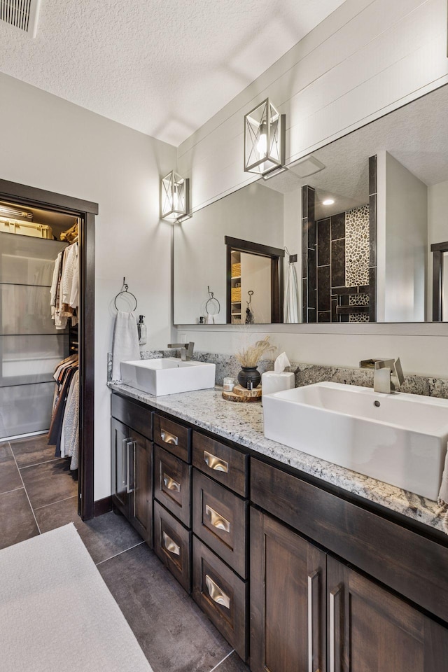 12105 285th St, Lindstrom, MN 55045 - full bathroom featuring double vanity, a textured ceiling, a spacious closet, and tiled shower